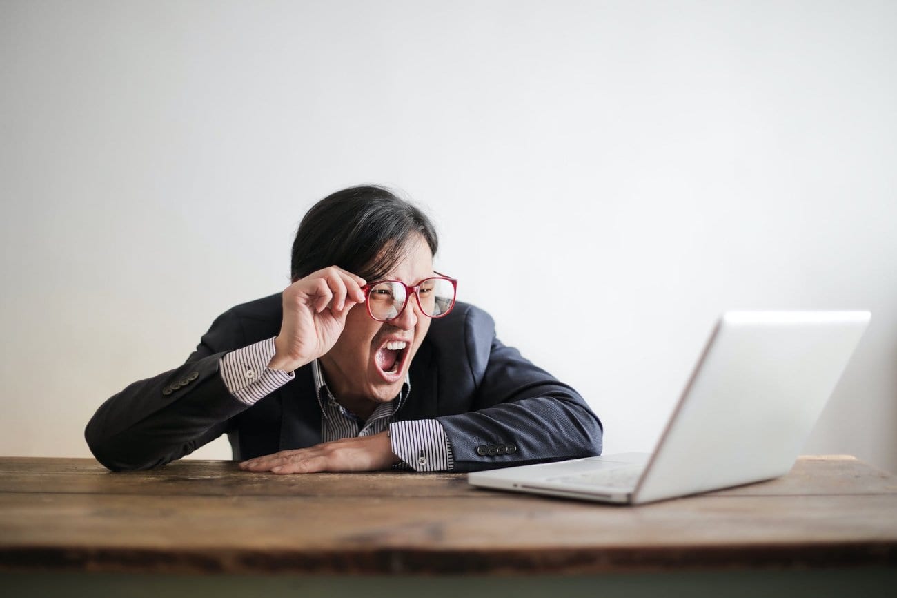 A man in a suit shouting in frustration at his laptop screen