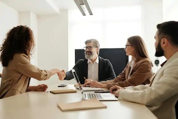 A candidate shaking hands with an interview panel across a meeting table