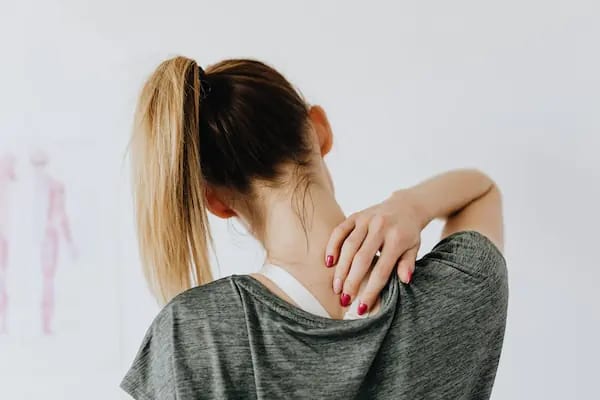 A woman holding the back of her neck in discomfort